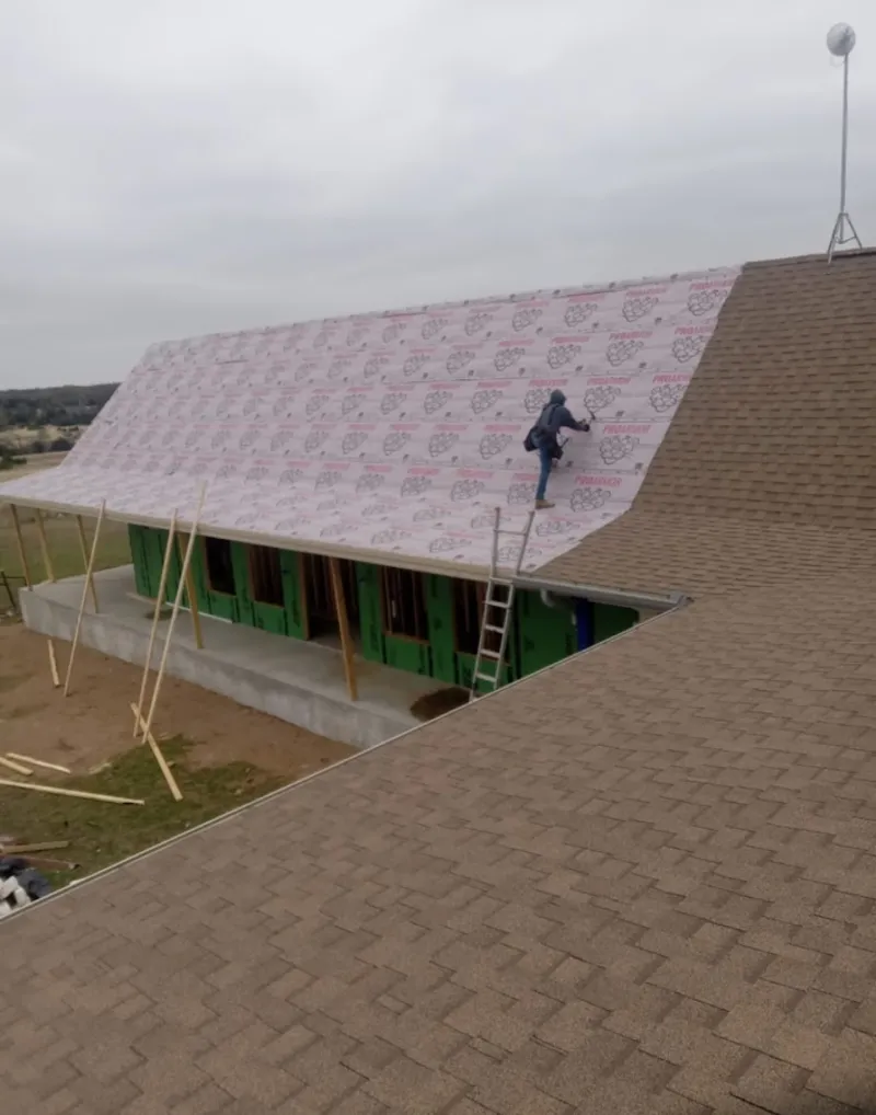 Worker preparing underlayment for a metal roof installation in Winterville
